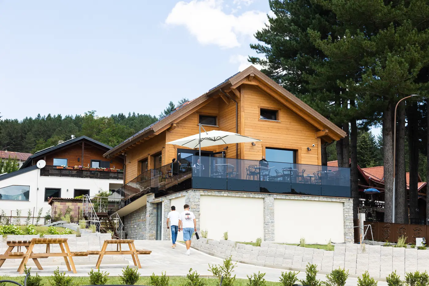 Il giardino con i tavoli di legno e il terrazzo dello Chalet
